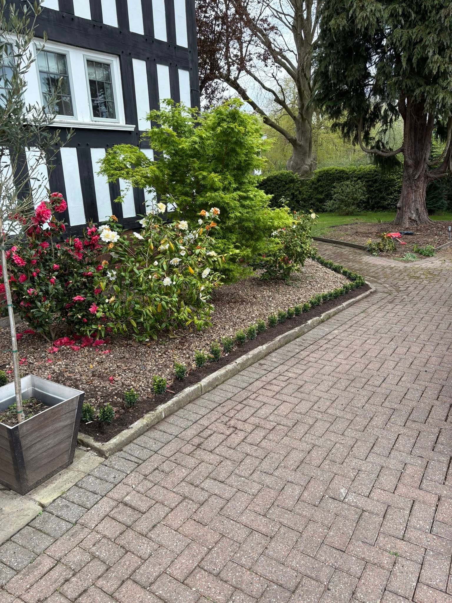 Tidy block-paved area with a planted border after garden clearance