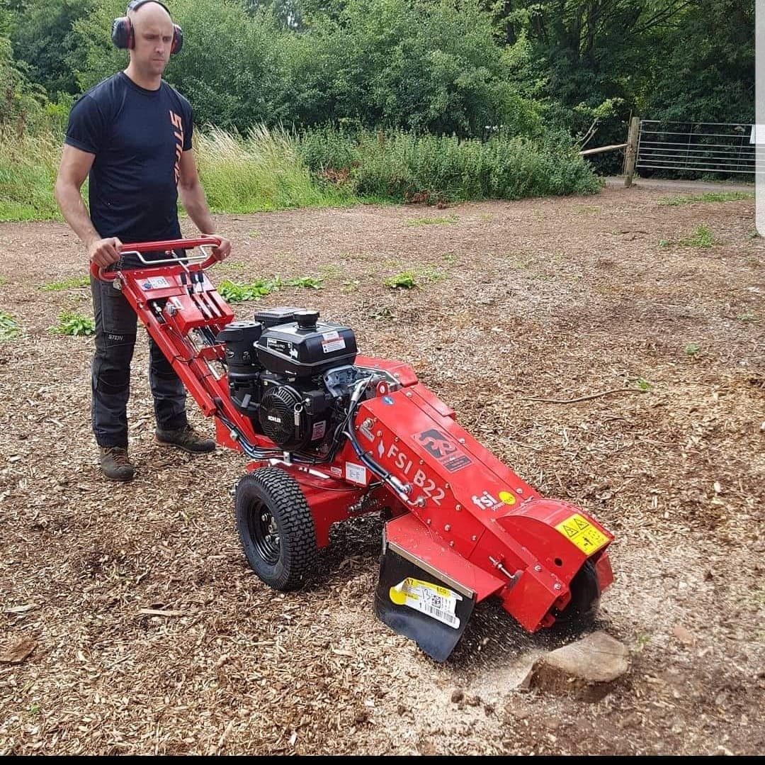 Operator grinding out a tree stump with a wheeled stump grinder